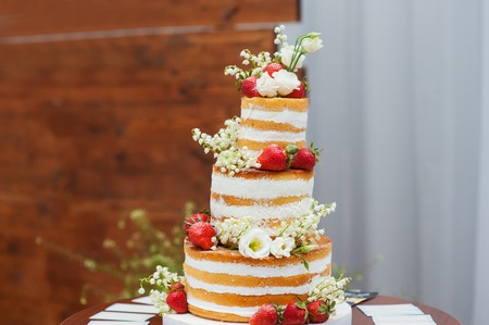 57590792 - three-tiered wedding cake with strawberries on table.